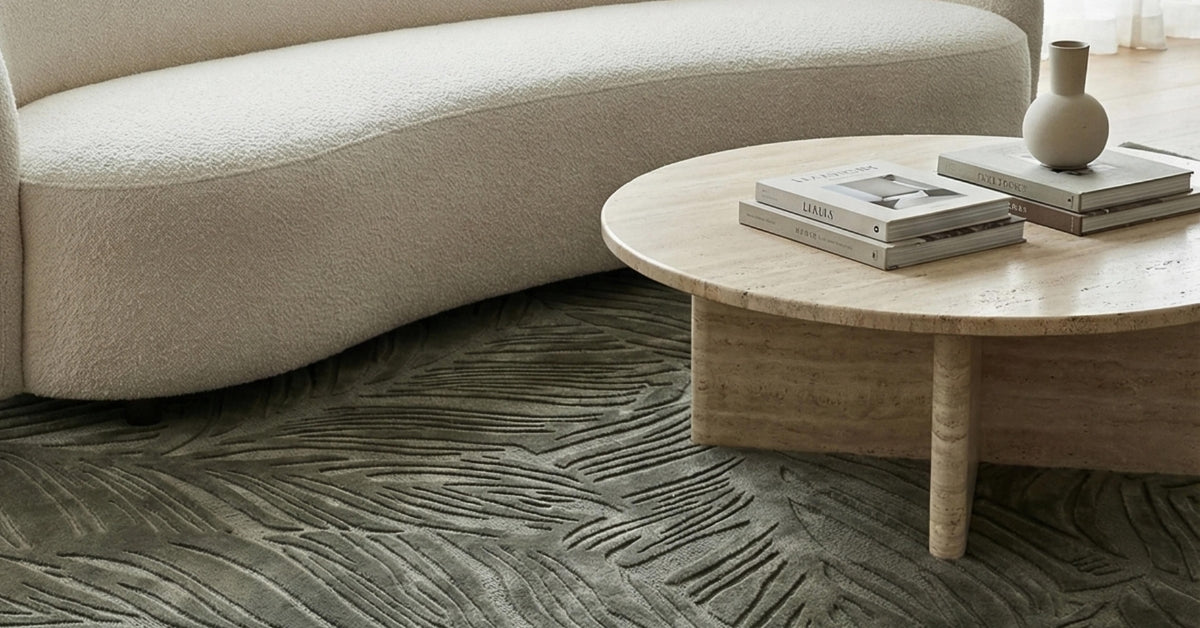 Green area rug styled in a living room with a white sofa and travertine coffee table