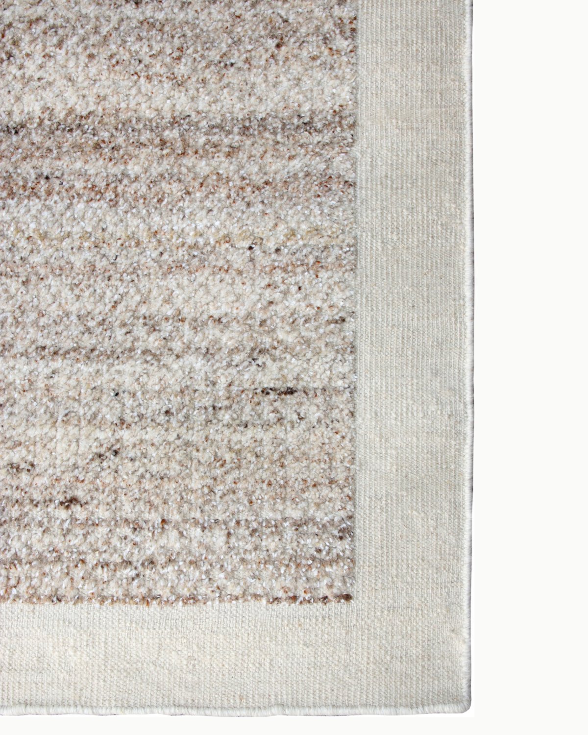 Curled corner of Akira hand-knotted wool rug in Dune, showing the woven back, hand-bound edge and pile thickness