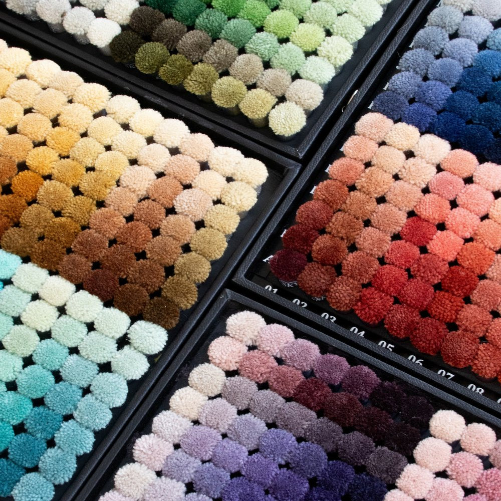 Wool pom colour swatches for House of Bohi custom rugs, displaying an extensive palette of natural, earth and jewel tones from soft neutrals to statement shades.