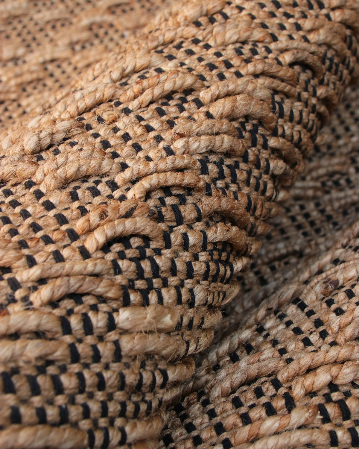 Extreme close-up highlighting the chunky tactile interplay of golden jute and black cotton warp for an organic texture.