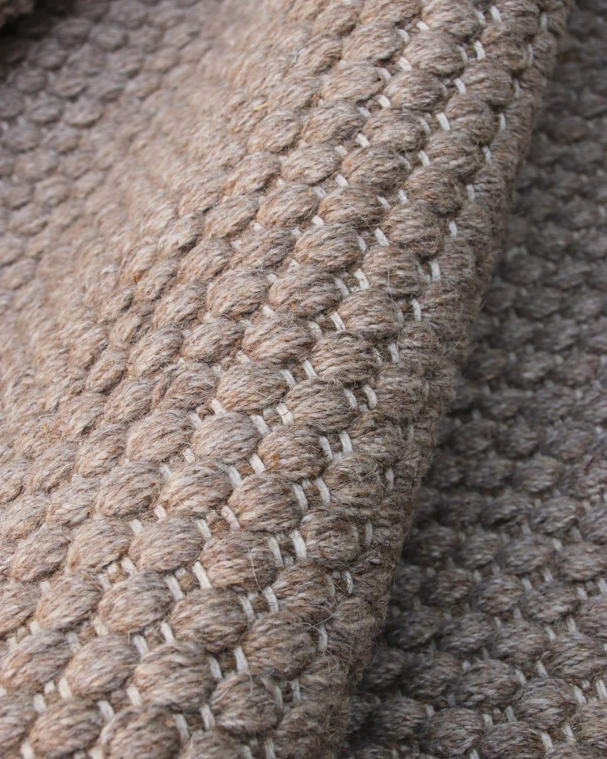 Macro detail highlighting the intricate beaded flatweave construction and quiet texture of the spun yarn.