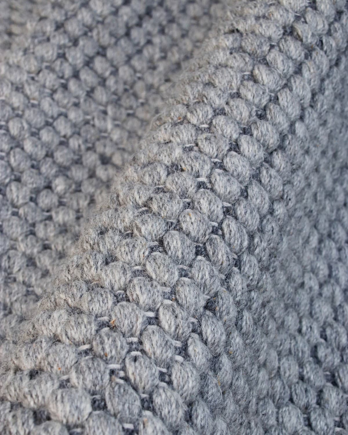 Macro detail highlighting the intricate beaded flatweave construction and quiet texture of the premium spun yarn.