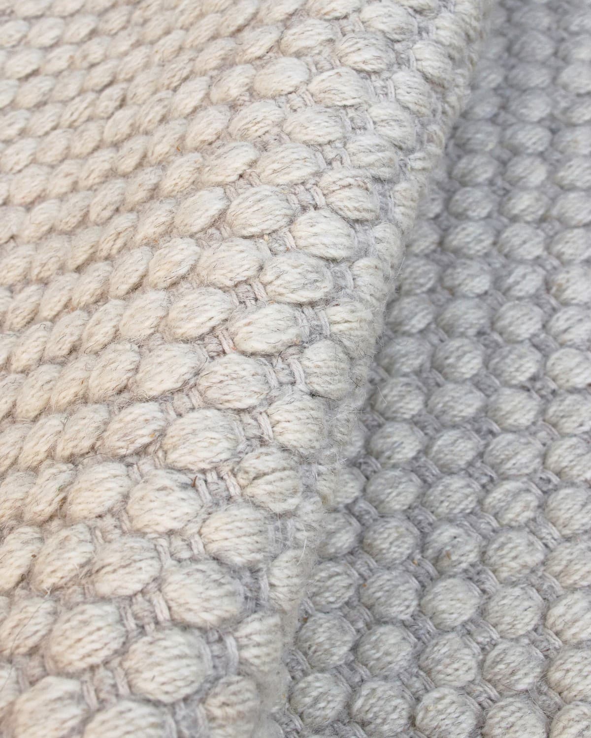 Macro detail highlighting the intricate beaded flatweave construction and quiet texture of the premium spun yarn.