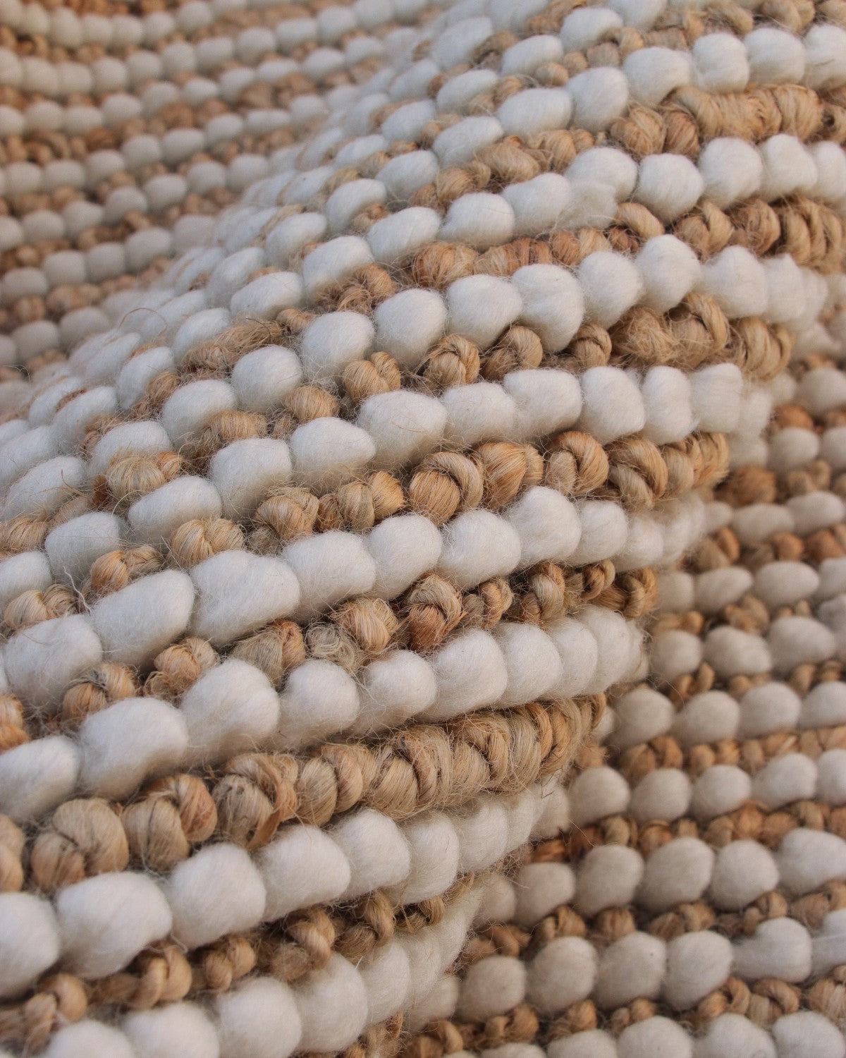 Extreme close-up highlighting the chunky, beaded texture of alternating New Zealand wool and raw golden jute stripes.