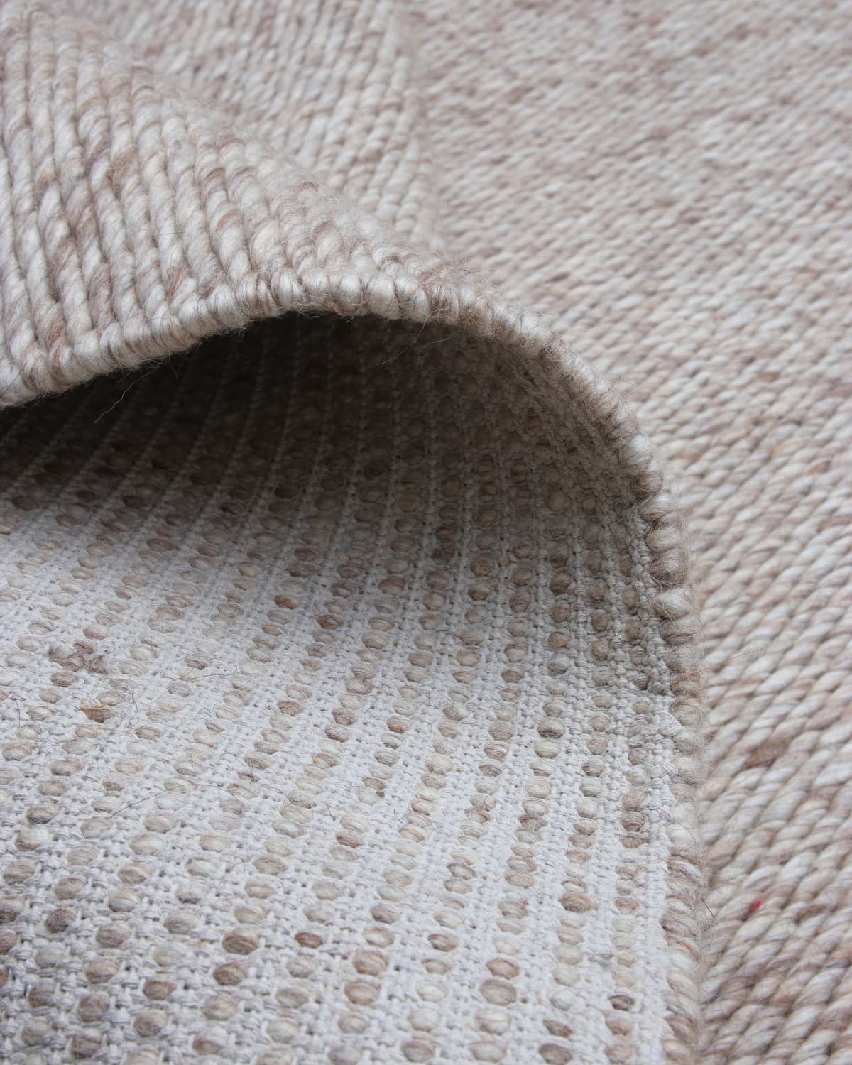 Folded corner showing the substantial 5000gsm weight. Handmade in Bhadohi and GoodWeave certified for a grounding bedroom.