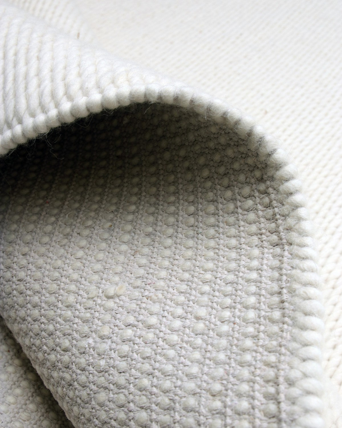 Folded corner highlighting the substantial 5000gsm profile. Ethically handmade in Bhadohi and GoodWeave certified for a bedroom.