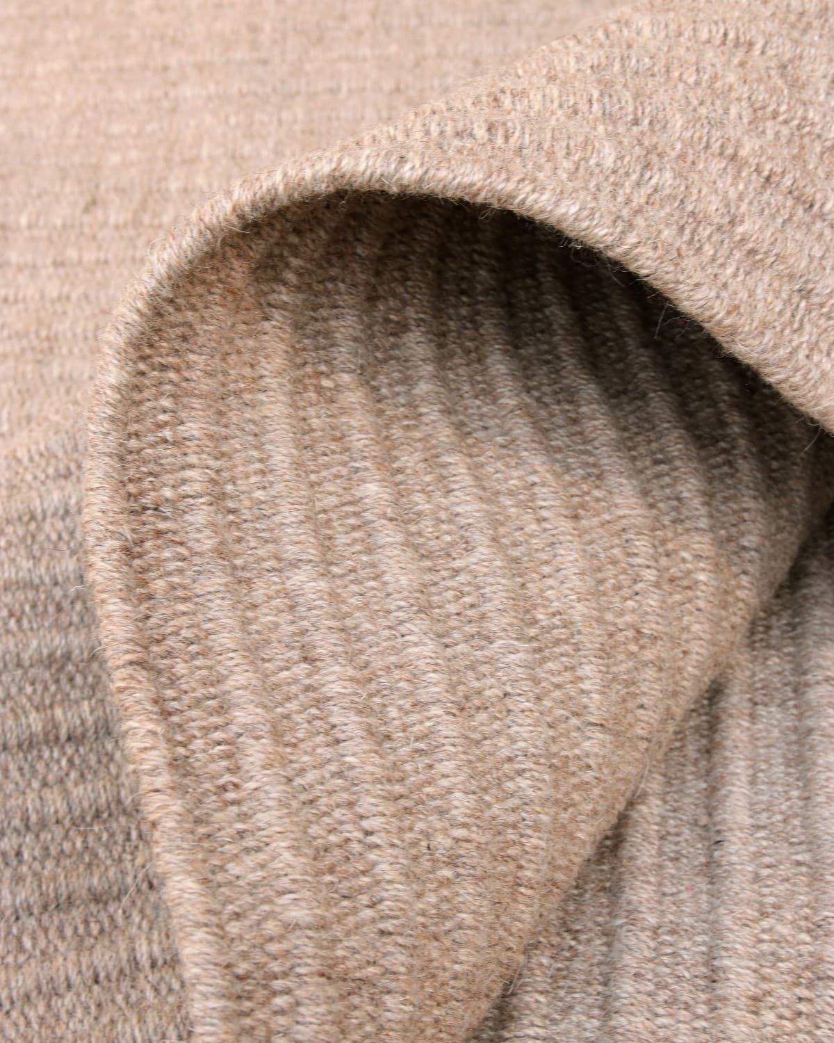 Folded reversible flatweave showing subtle tactile relief and a 12mm pile height, ideal for a structured living room.