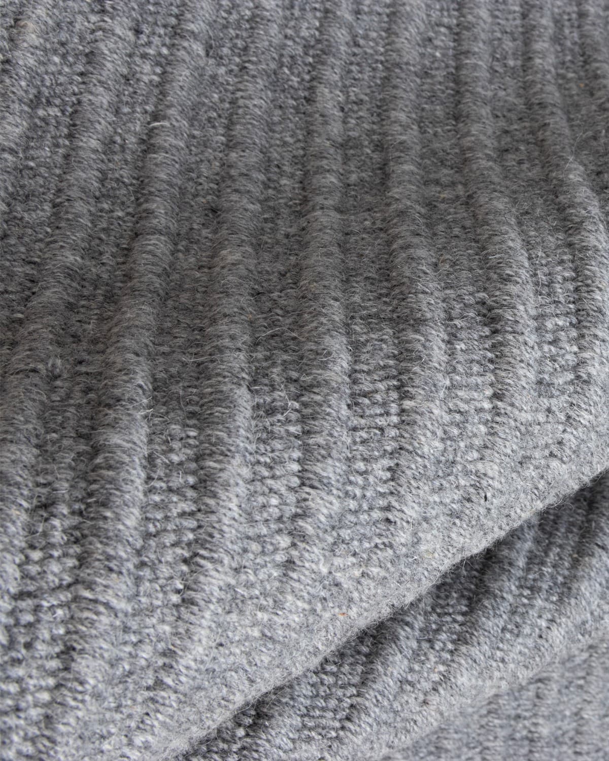 Draped reversible flatweave revealing subtle tactile relief and a 12mm pile height, ideal for a structured living room.