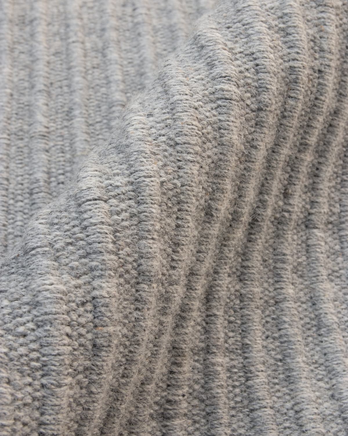 Wavy draped flatweave showing subtle tactile relief and a 12mm pile height, perfect for a calming bedroom.