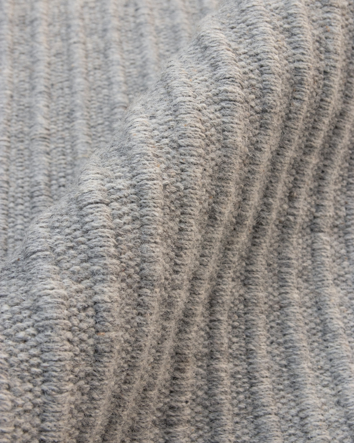 Wavy draped flatweave showing subtle tactile relief and a 12mm pile height, perfect for a calming bedroom.