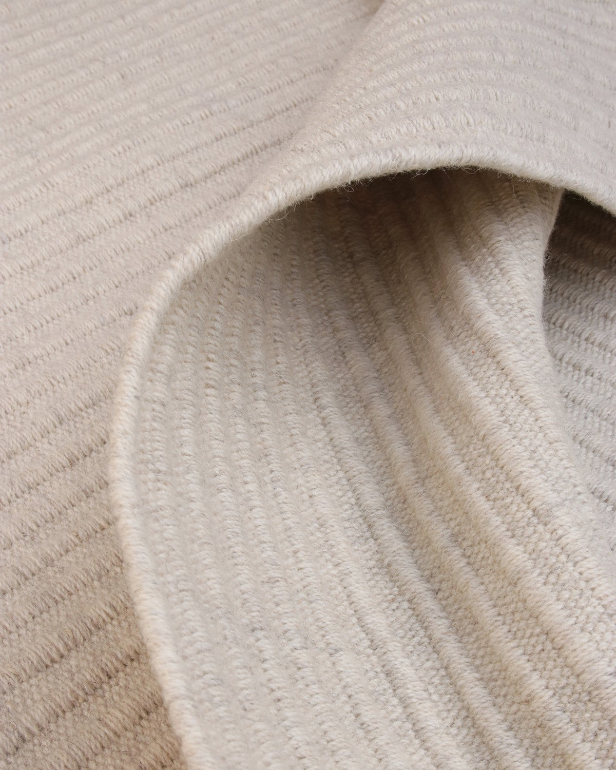 Folded corner revealing the quiet rhythm of its linear form, ethically handmade in Bhadohi, India.