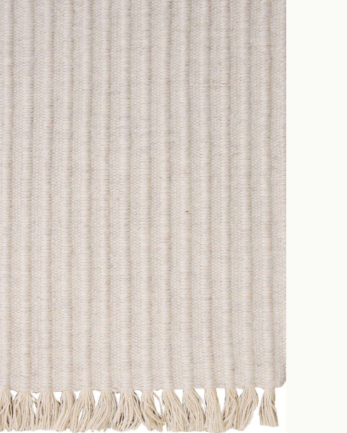 Detailed look at the playful fringe edge of this ivory wool rug, GoodWeave certified and ideal for a bedroom.
