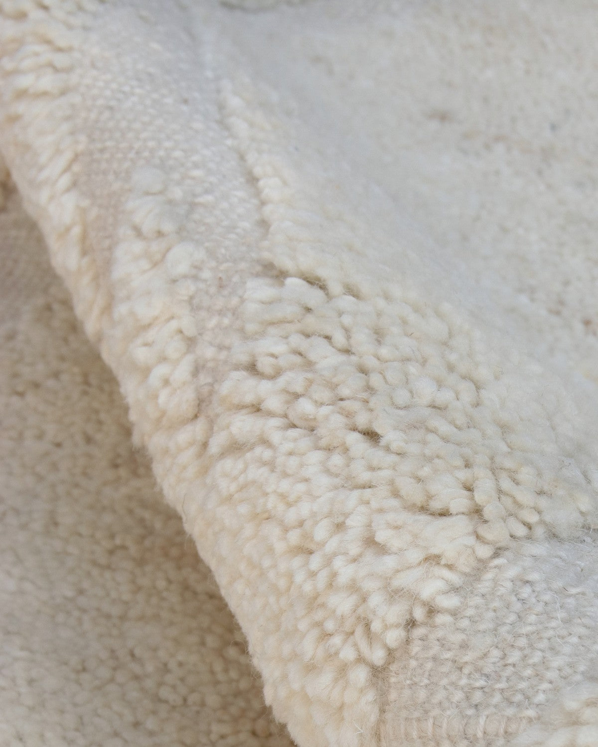 Close-up of undyed wool highlighting a sculptural 10mm pile height, ethically handmade by GoodWeave certified artisans.