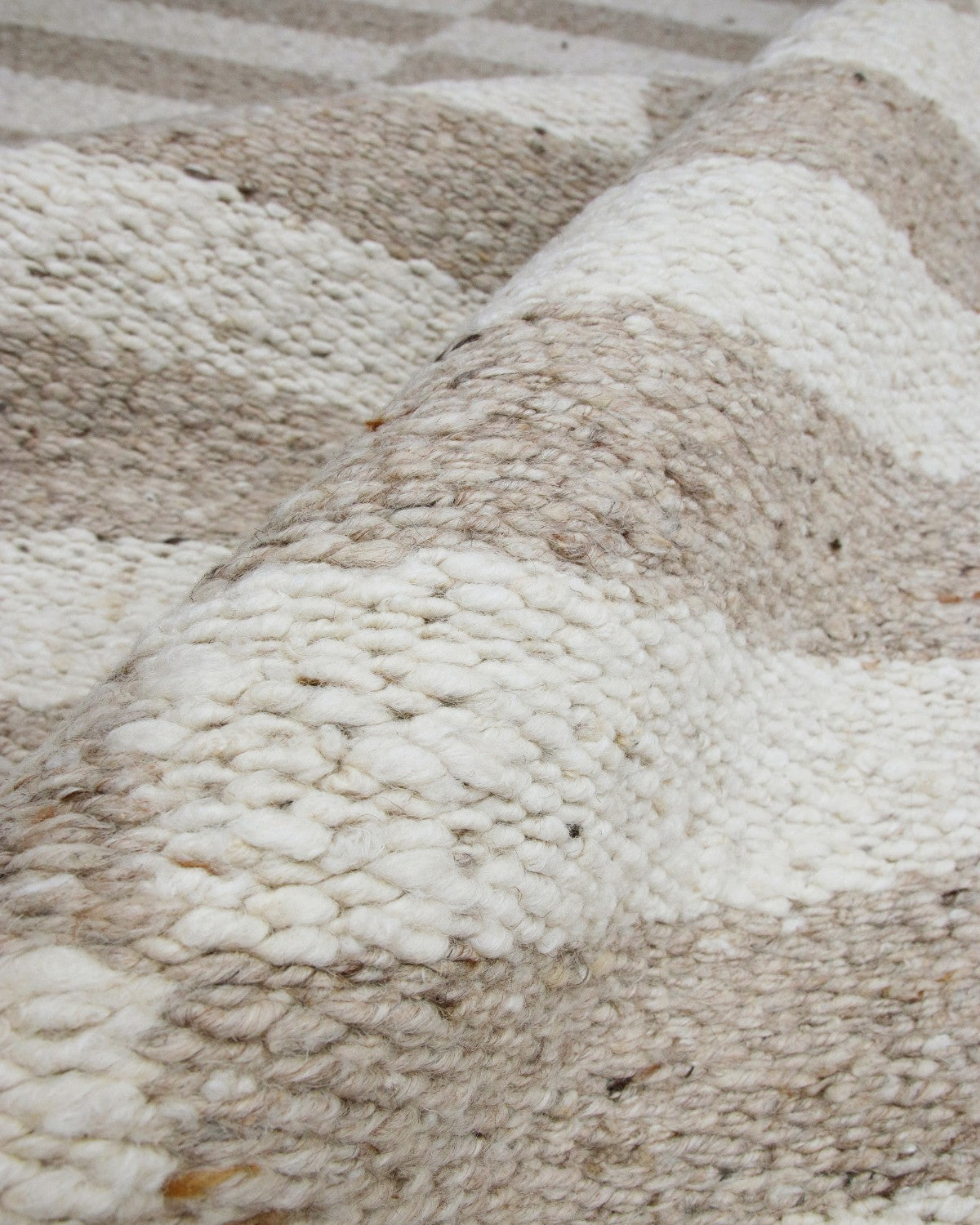 Folded edge revealing undyed organic tonal variations, a 12mm pile height, and GoodWeave certified ethical construction.