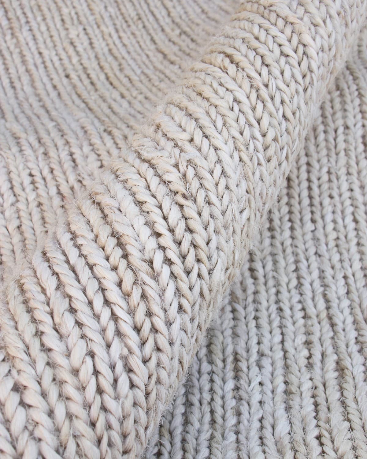 Close up of the handwoven flatweave technique revealing a braided texture that brings a relaxed, structural rhythm to the space.
