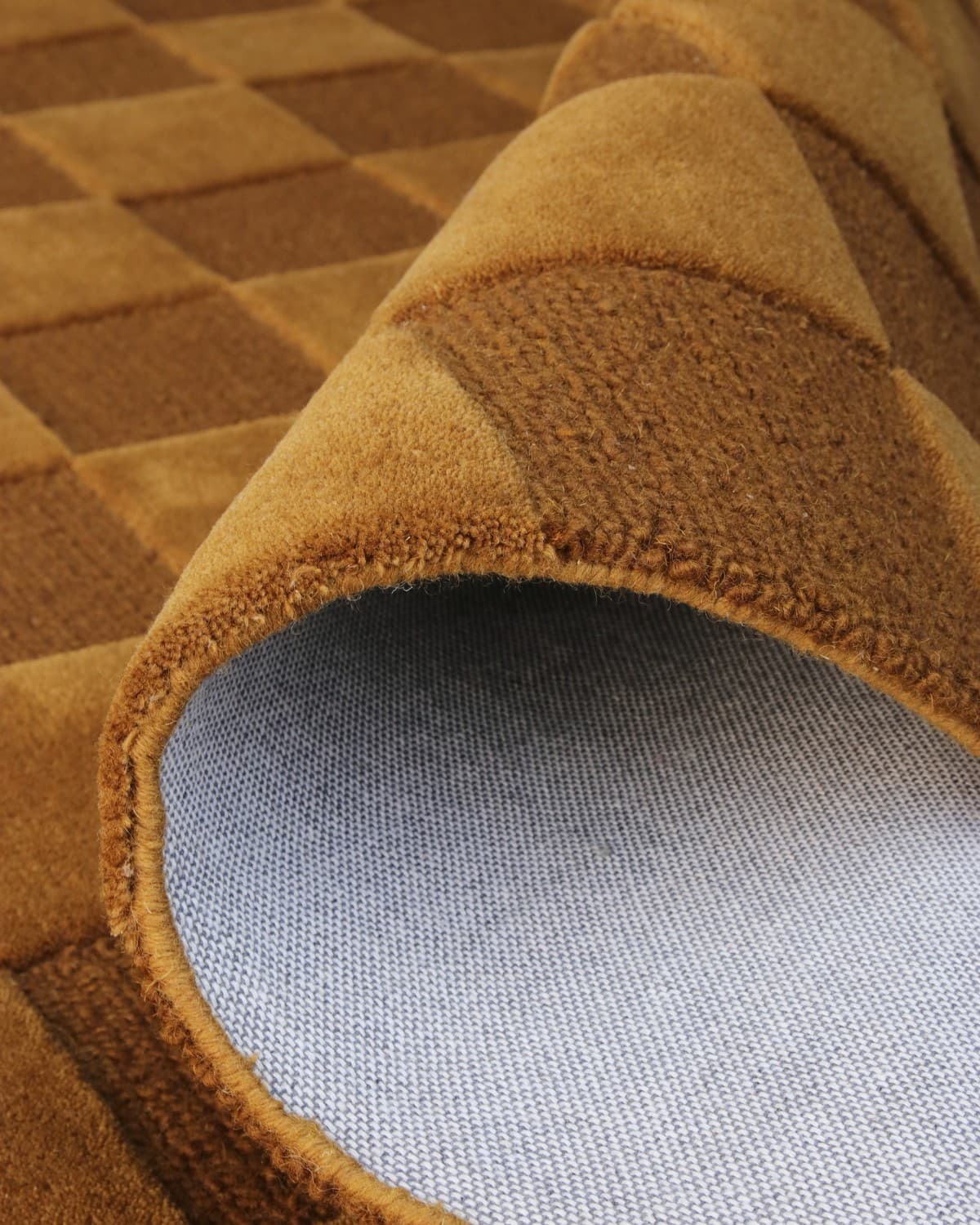 A folded corner reveals the durable backing and neat edge finishing of this GoodWeave Certified, ethically made wool rug.