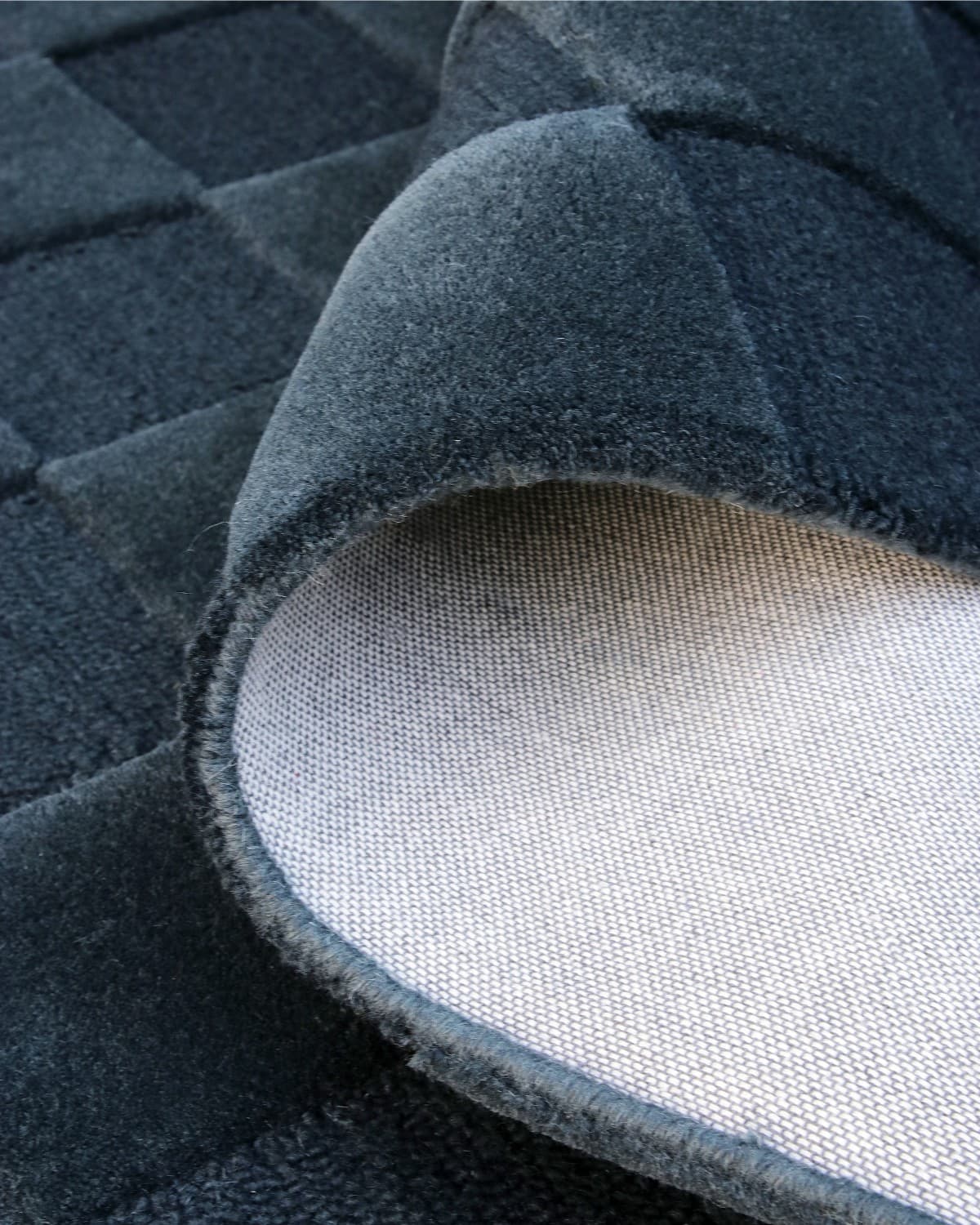 A folded corner displays the durable backing and neat edge finishing of this GoodWeave Certified, ethically produced rug.