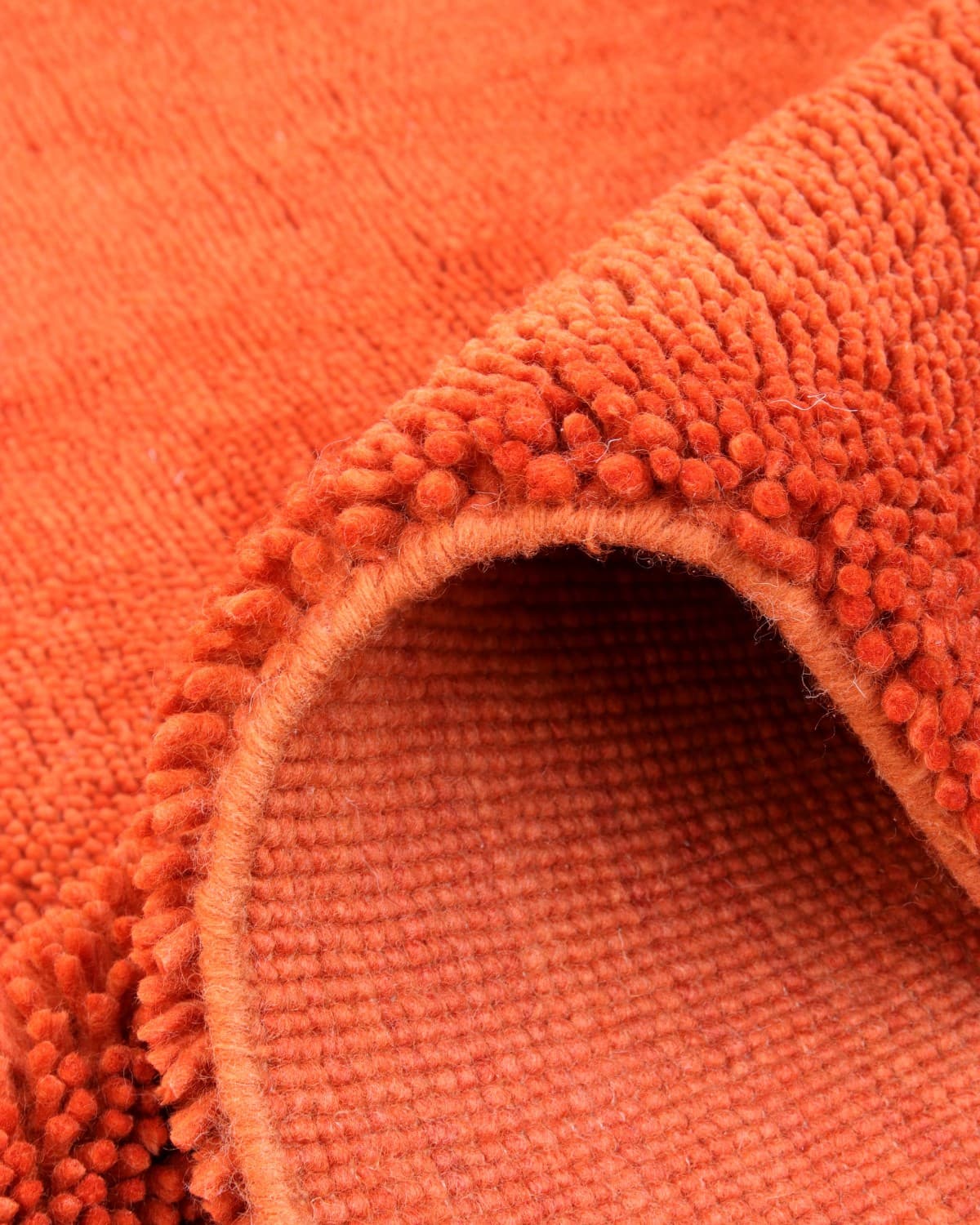 Folded corner revealing the sturdy woven backing and thick, comforting natural fibers.