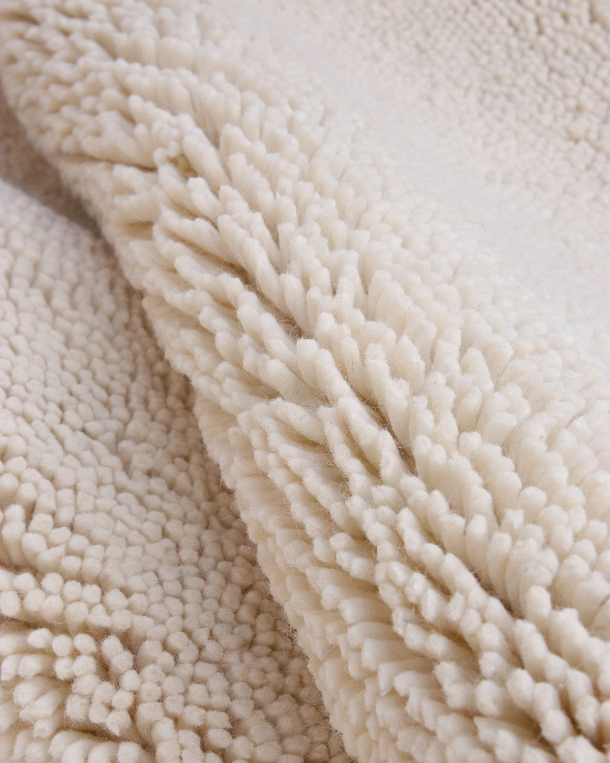 House of Bohi Raya area rug in ivory. A modern shag crafted from felted New Zealand wool with a thick, nubby texture.