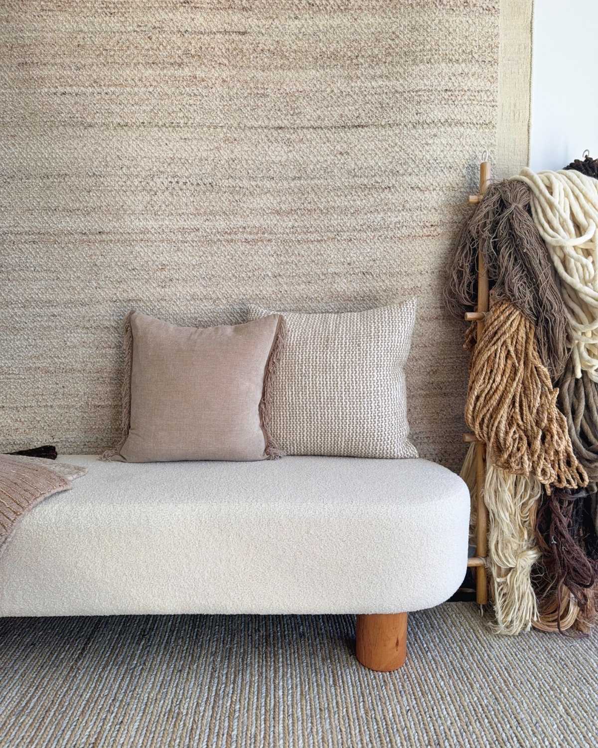 House of Bohi rug studio in Kirrawee, Sydney, with handmade rugs displayed on wall and floor along with rug samples and hanks of natural fibres like wool, jute and tencel displayed on a ladder.