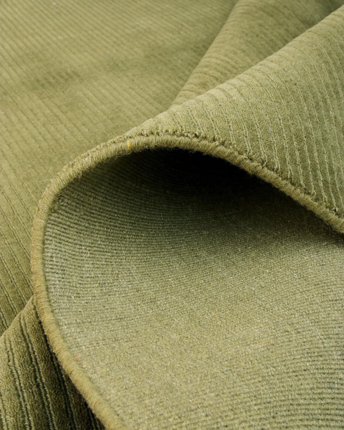 Folded olive floor covering highlighting crisp edge definition. This GoodWeave certified piece suits living rooms.