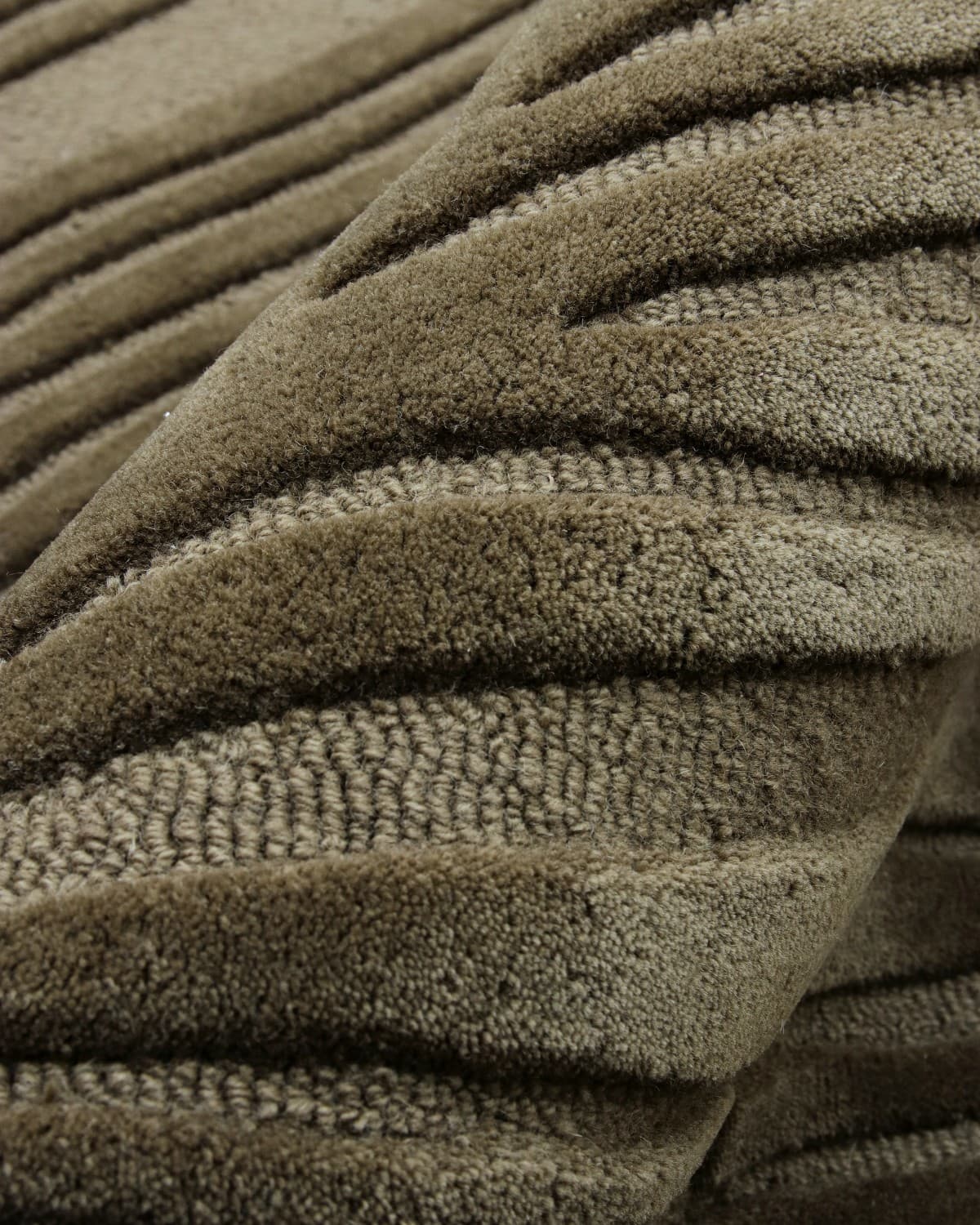 Macro detail of handtufted cut and loop pile. A dense 15mm pile height offers a rhythmic, organic presence for living rooms.