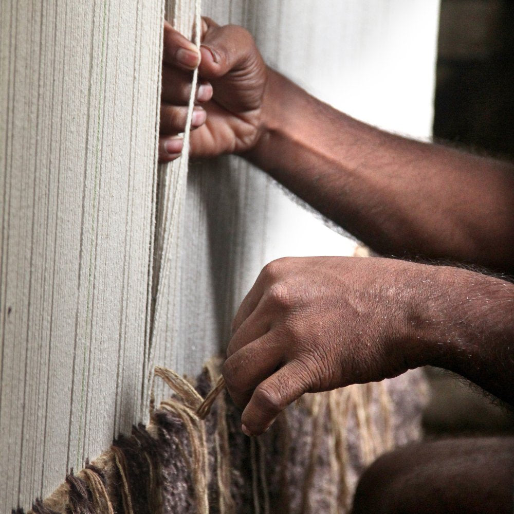 Artisan hand-knotting a custom rug on a traditional vertical loom at the House of Bohi workshop in Bhadohi, India, using techniques passed through four generations.