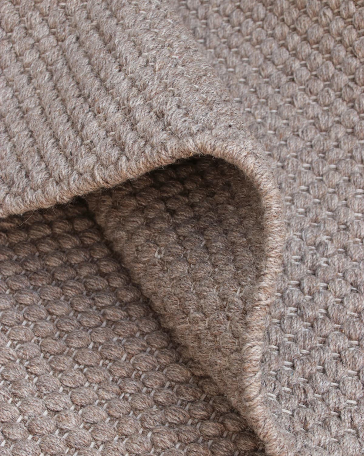 Folded drape showcasing the soft, beaded texture of premium New Zealand wool and a low 12mm pile height.
