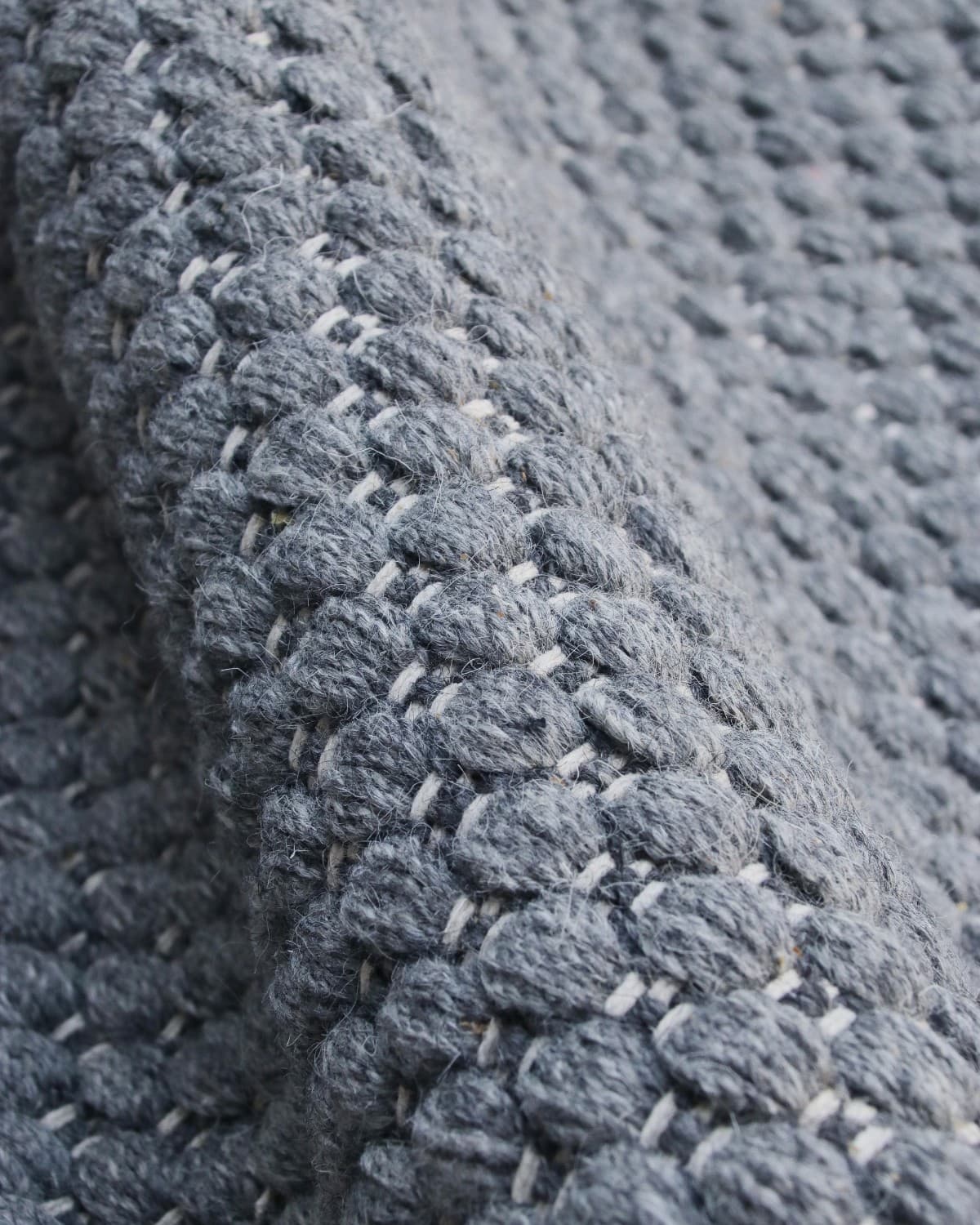 Macro detail highlighting the intricate beaded flatweave construction and quiet texture of the premium spun yarn.
