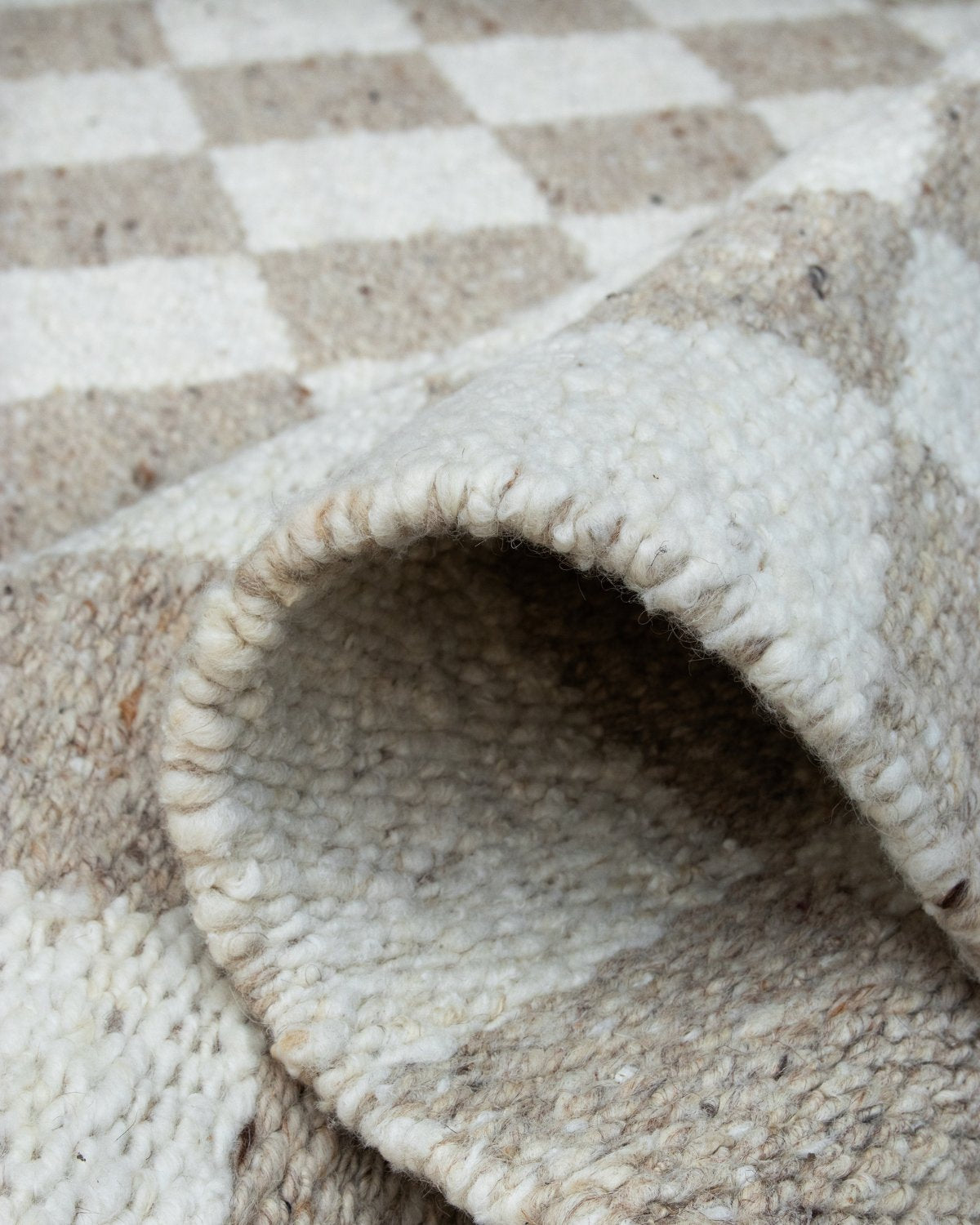 Folded corner highlighting the durable structure, handwoven by artisans in Bhadohi to ground a serene living room or study.