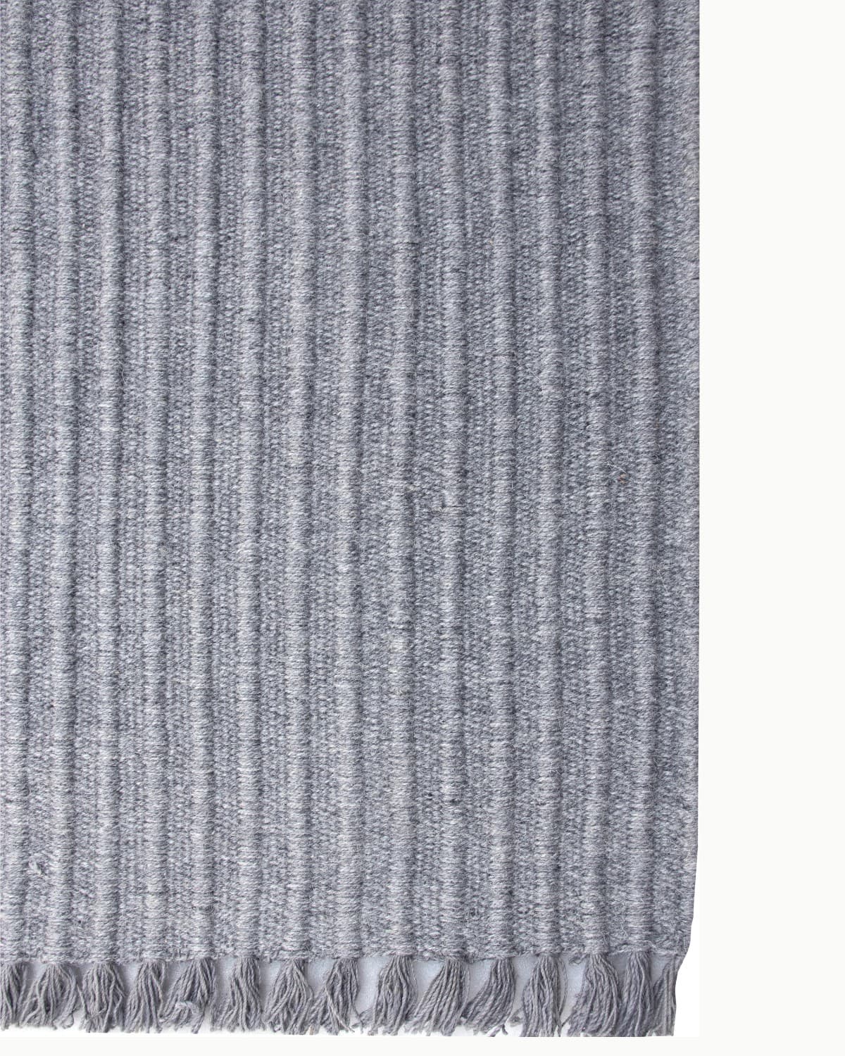 Detailed look at the playful fringe edge of this charcoal wool rug, GoodWeave certified and perfect for a calming bedroom.
