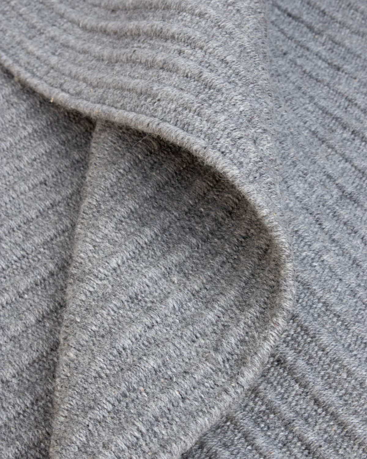 Macro view highlighting the quiet rhythm of the linear ribbed form, ethically handmade in Bhadohi, India.