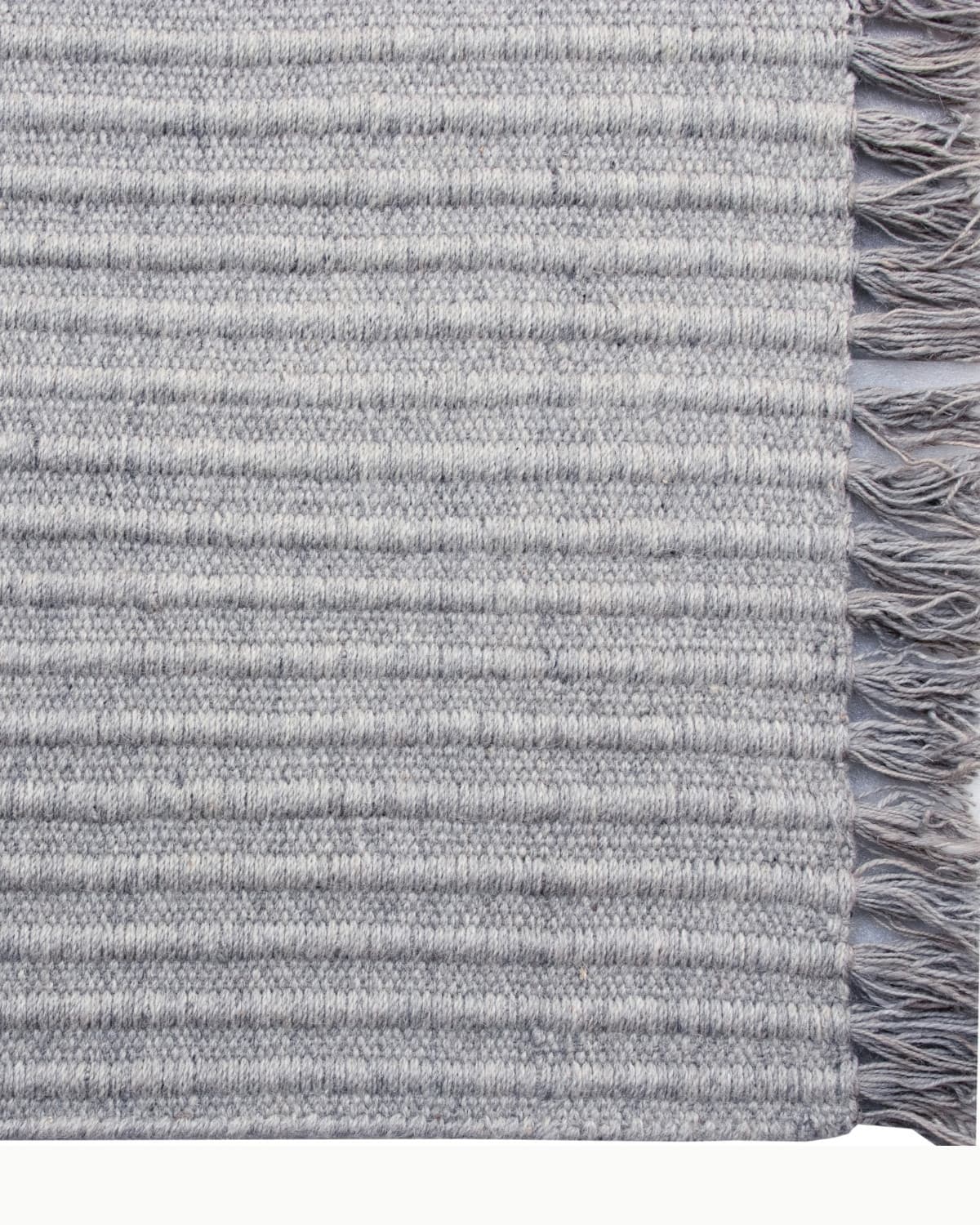 Playful fringe edge of a grey flatweave runner, GoodWeave certified and handmade in Bhadohi, India for an entryway.