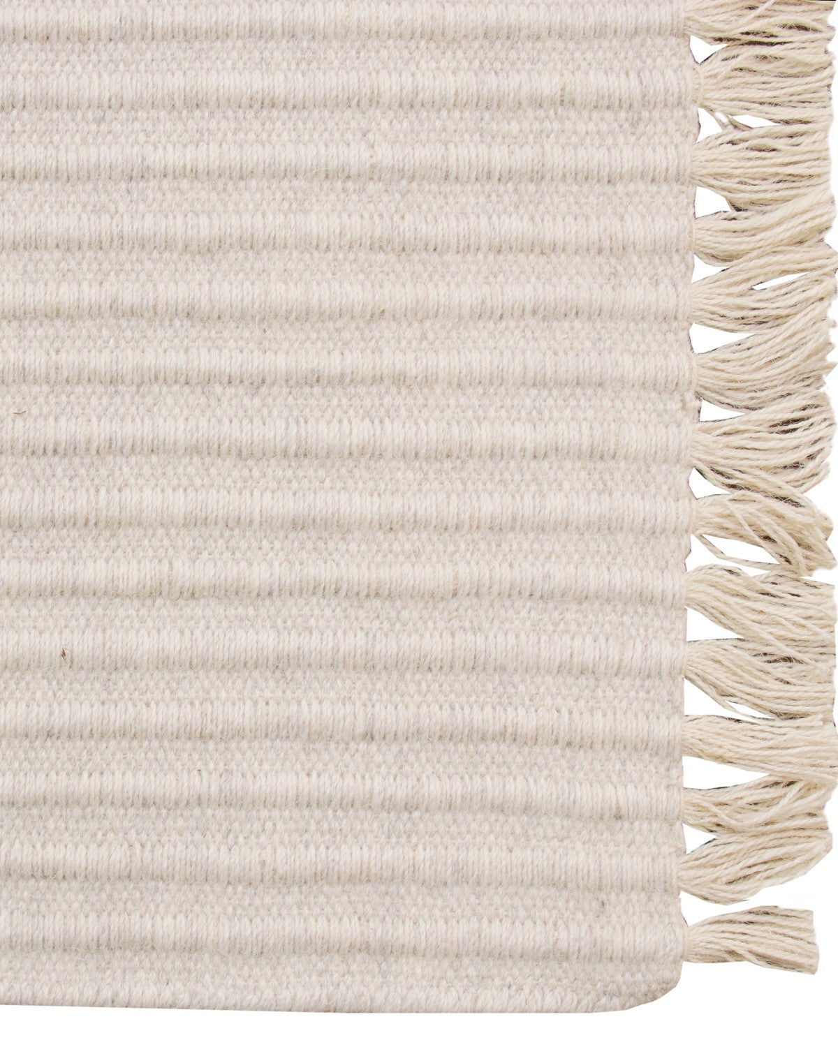 Playful fringe edge of an ivory flatweave, GoodWeave certified and ethically handmade in Bhadohi for an entryway.