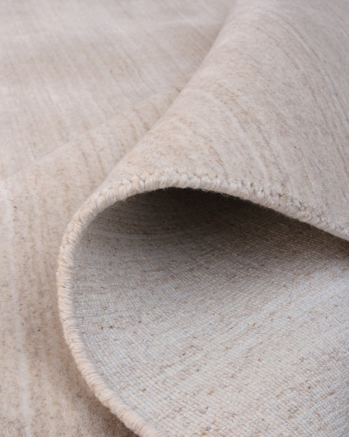 Folded handloomed fabric evoking wind-swept lines of a sand dune, fully GoodWeave certified for ethical production.