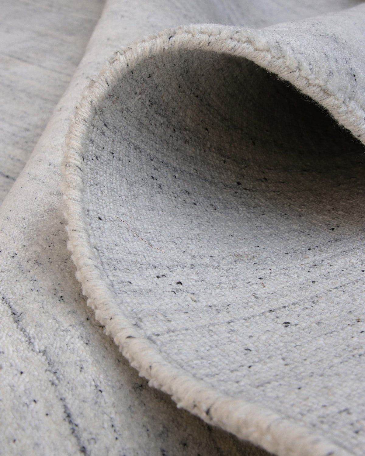 Folded handloomed fabric evoking wind-swept lines of a sand dune, fully GoodWeave certified for ethical production.