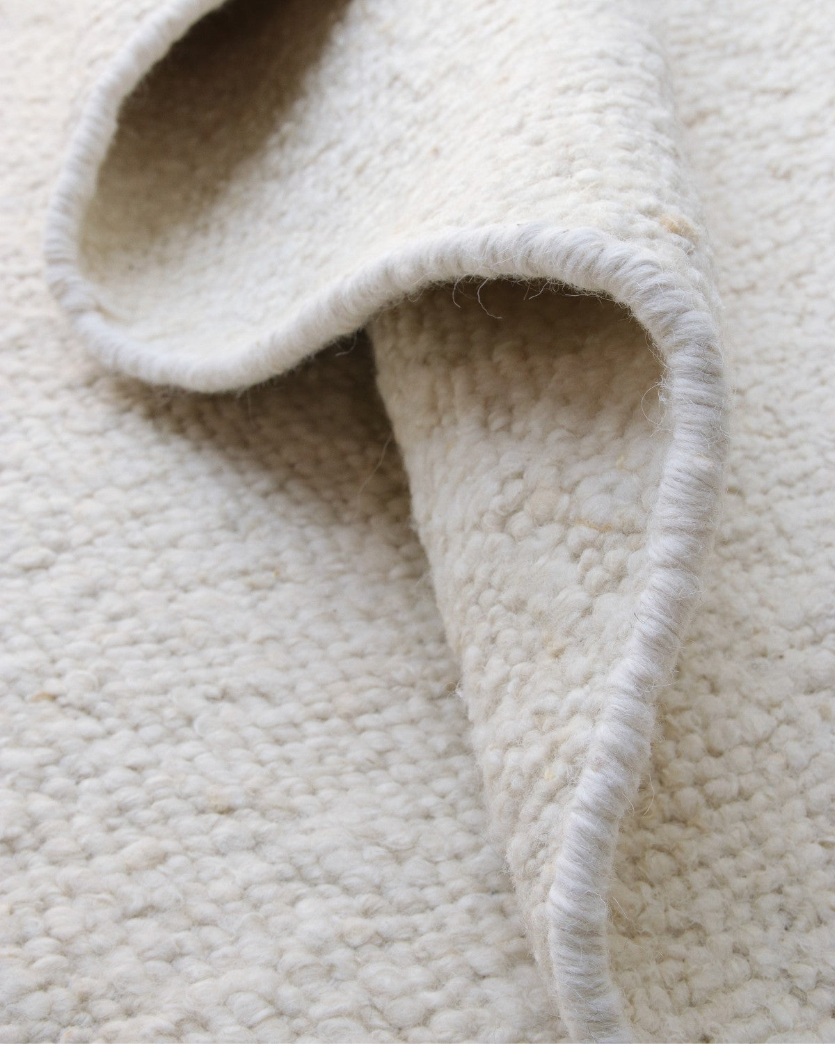A soft corner drape highlights the neat edge binding and resilient 12mm pile, bringing quiet character to a living room or study.