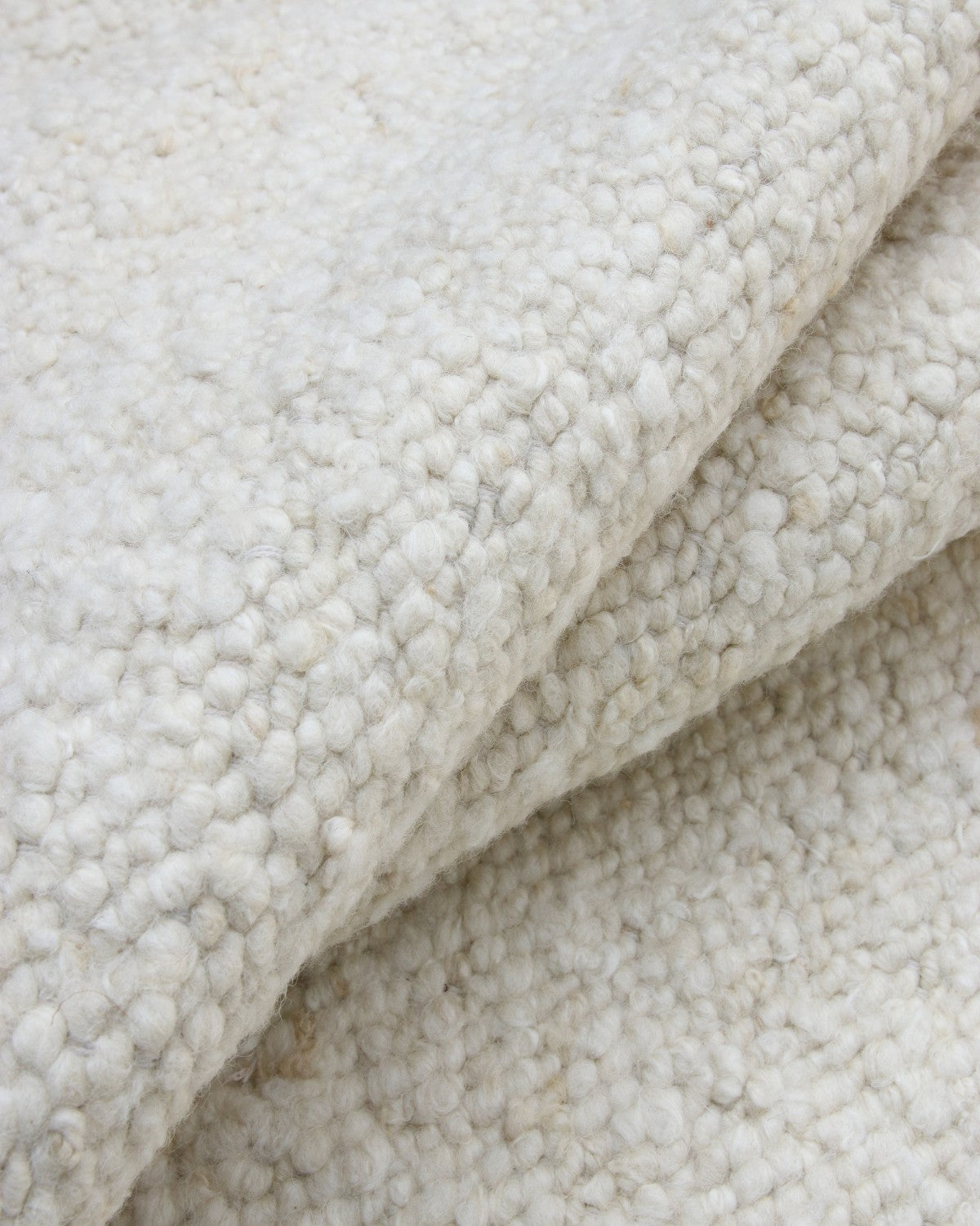 Close up of the hand-carded wool revealing organic tonal variations for a rustic and refined heathered surface.