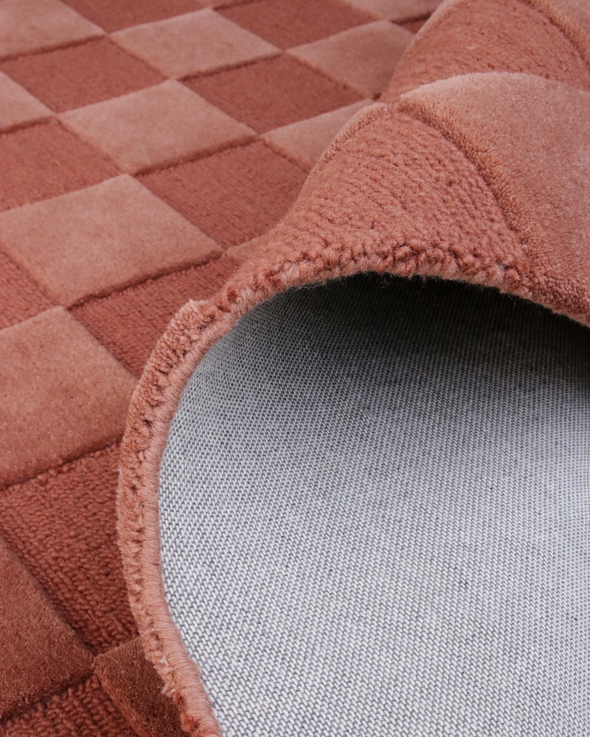 A folded corner reveals the durable backing and neat edge finishing of this GoodWeave Certified, ethically made wool rug.
