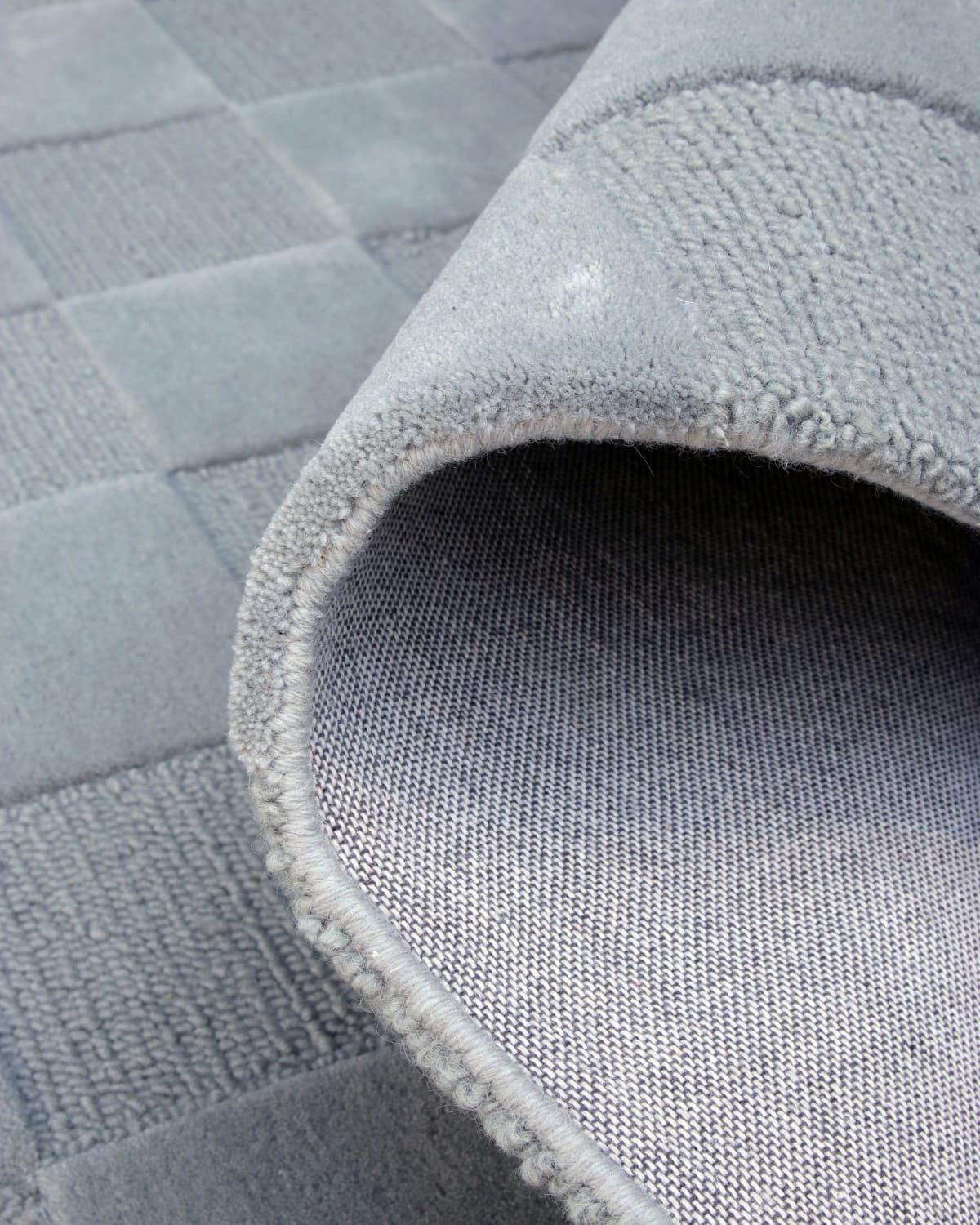 A folded corner displays the durable backing and neat edge finishing of this GoodWeave Certified, ethically produced rug.
