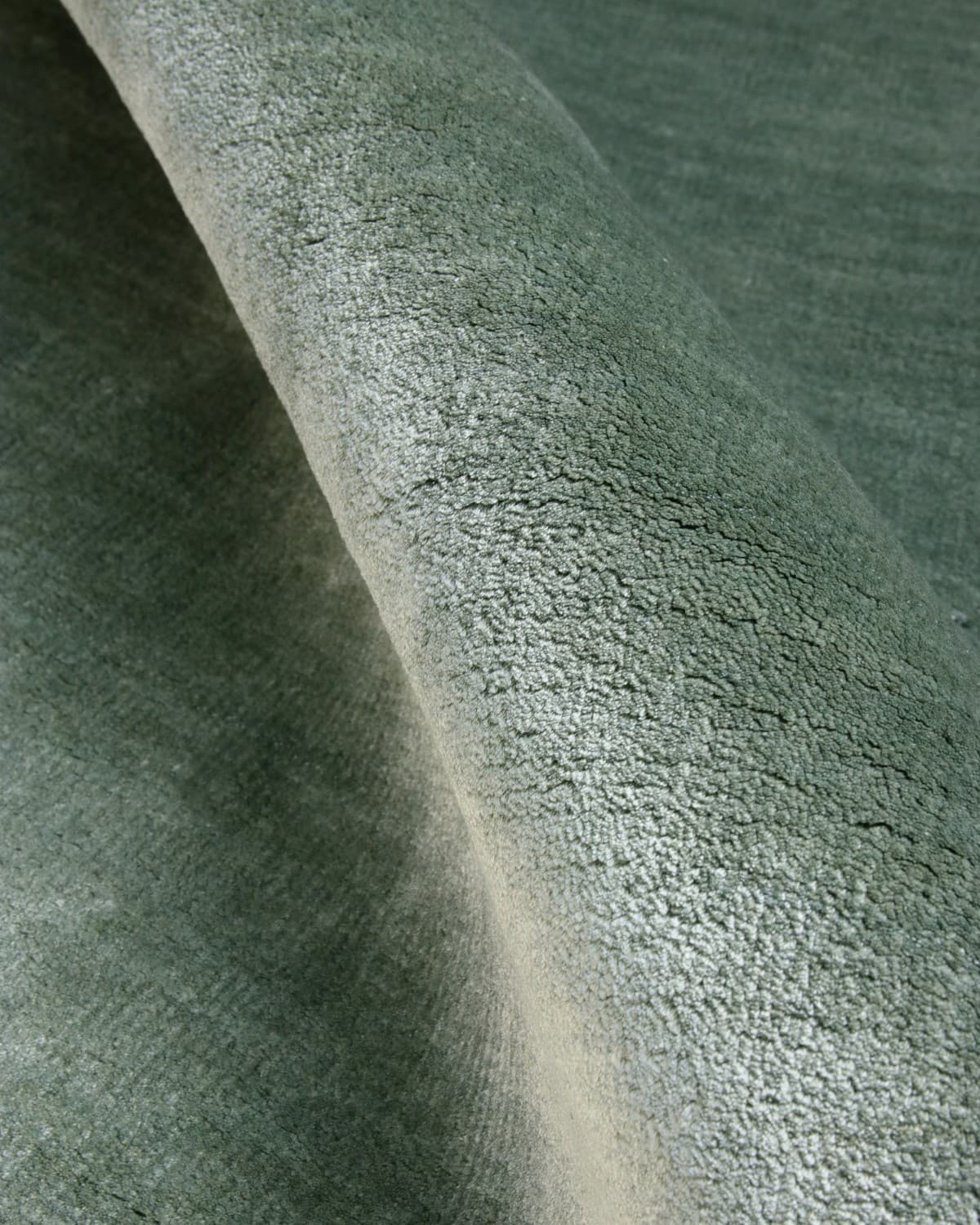 Close up of the handloomed surface, showcasing the natural fibres and a shifting landscape of sheen and shadow.