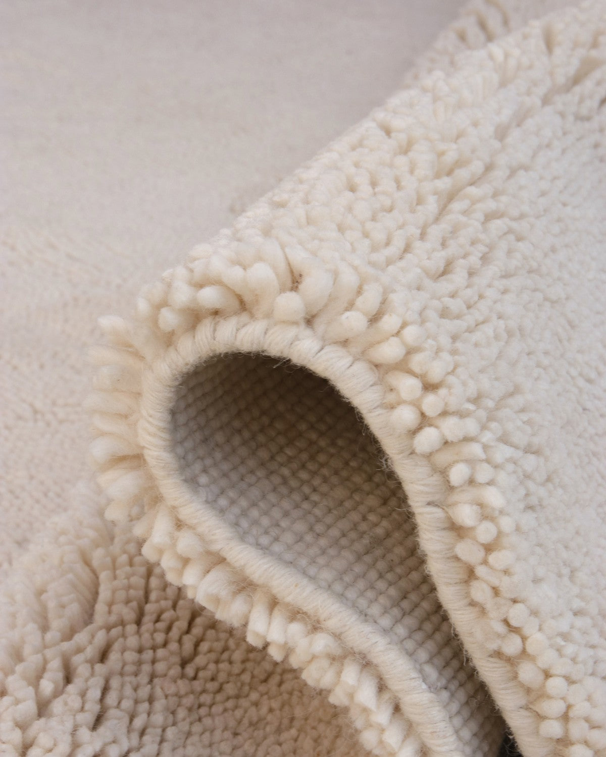 Folded corner revealing a sturdy canvas backing and dense 25mm high pile. This ethical design is GoodWeave Certified.