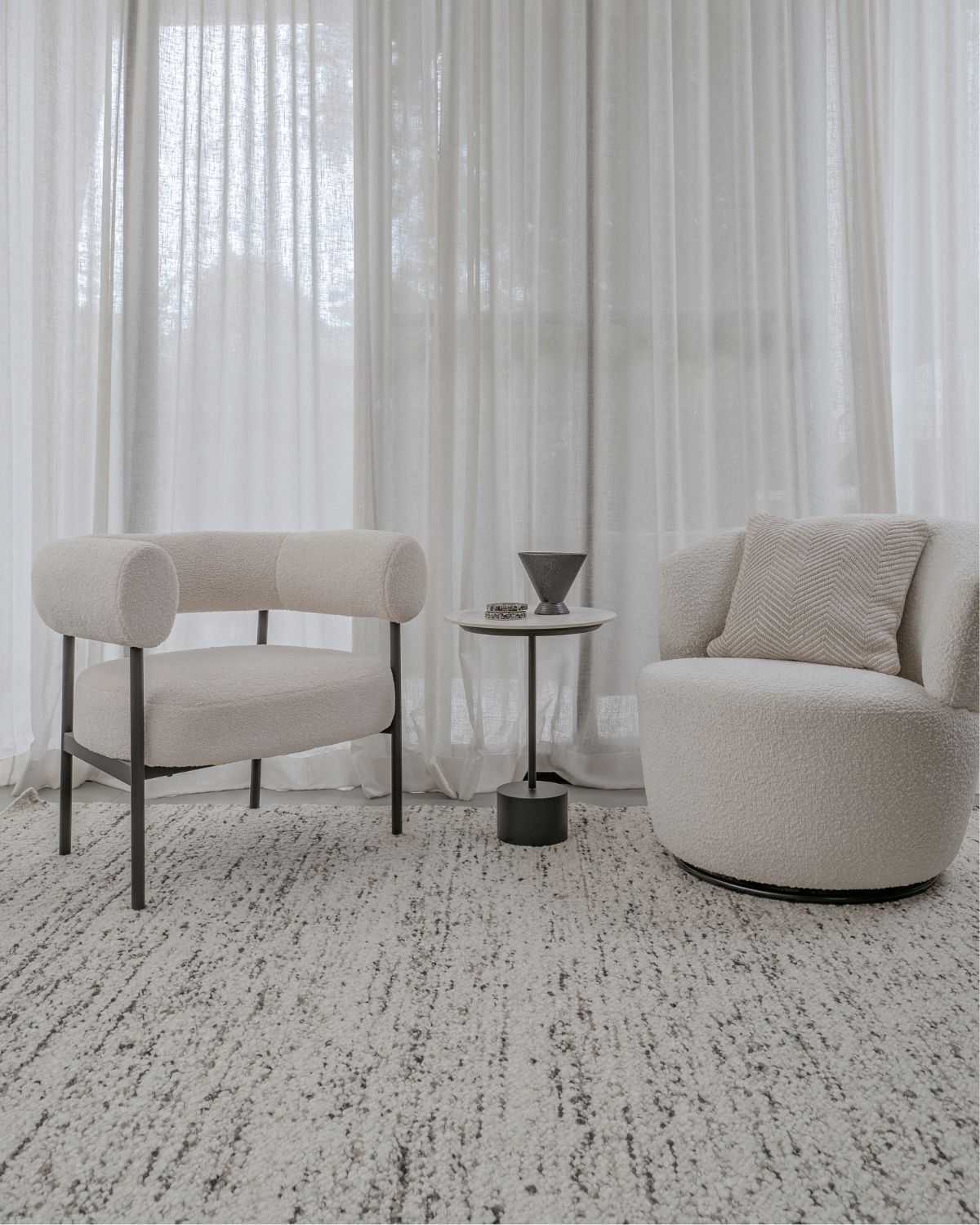 Taalo Ashstone undyed wool rug by House of Bohi, styled in a contemporary Sydney interior with sculptural cream armchairs, showcasing its plush handwoven flatweave texture and natural ash grey, ivory and charcoal tones.