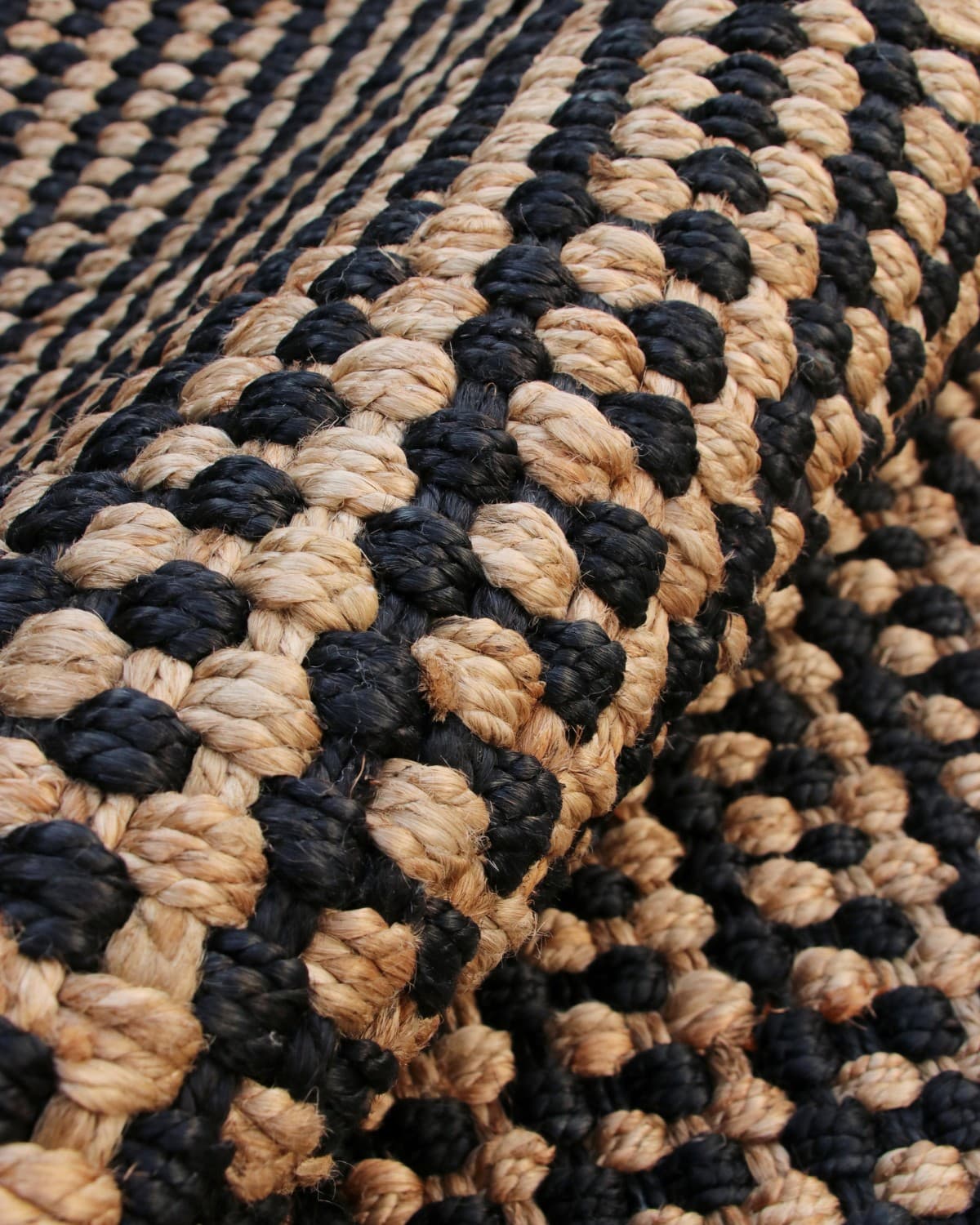 Macro detail of the chunky basketweave and thick sustainable knots. A durable flatweave bringing earthy warmth to nooks.