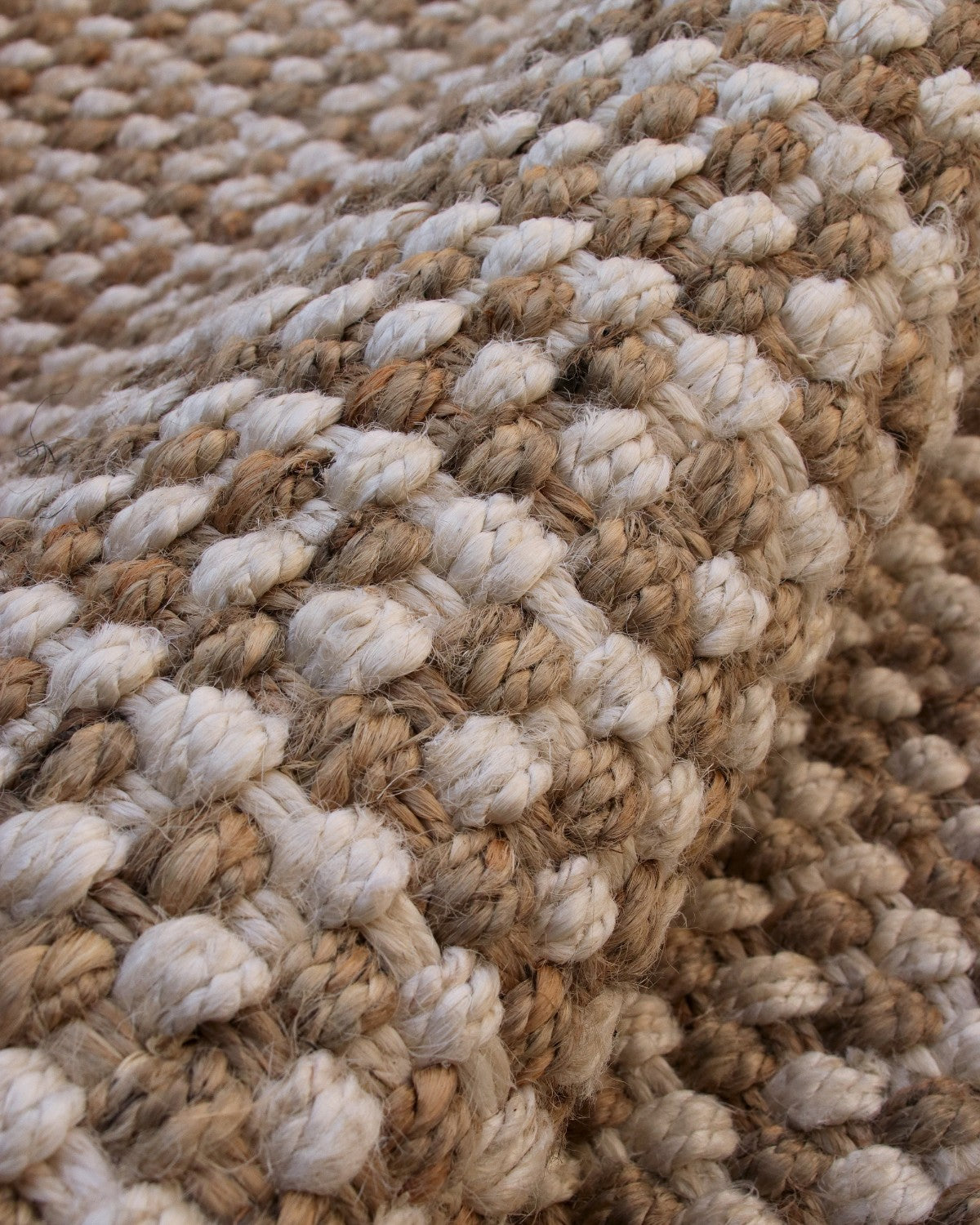 Macro detail of the chunky basketweave and thick sustainable knots. A handwoven flatweave ideal for living rooms.