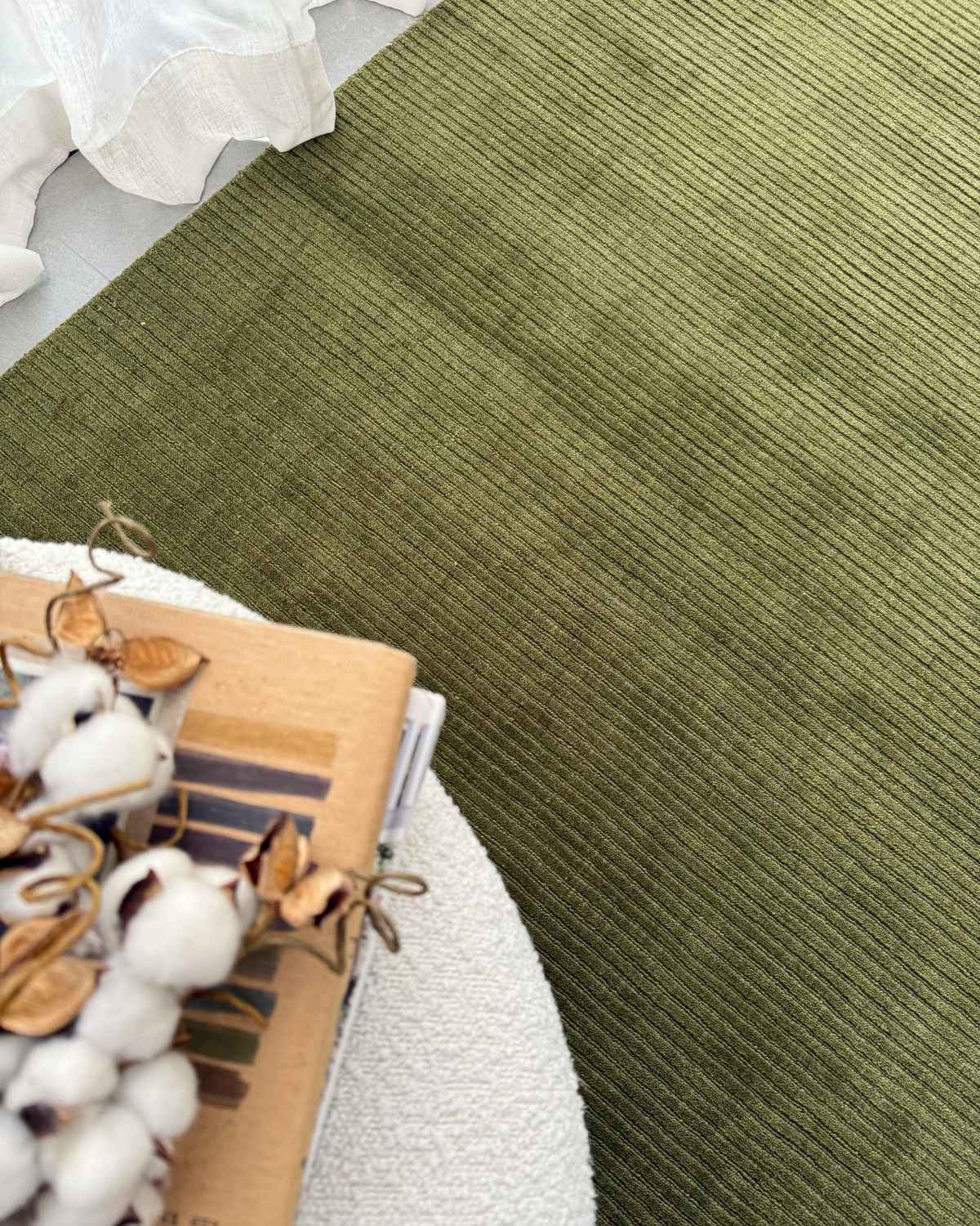House of Bohi handloom olive green wool rug with fine ribbed texture, styled in a neutral interior