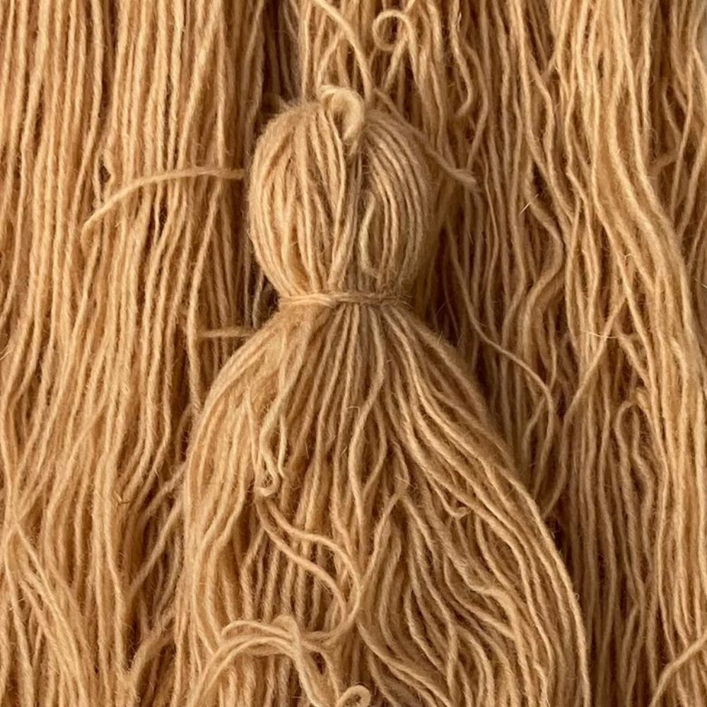Skeins of naturally dyed hand-spun wool yarn in warm tan tones, prepared for hand-weaving at the House of Bohi artisan workshop in Bhadohi, India.