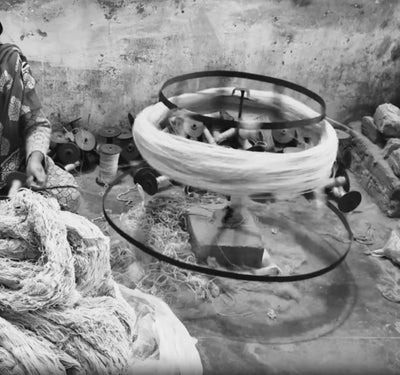 A weaver hand-spins wool and natural fibre into yarn on a traditional spinning wheel at the House of Bohi workshop in Bhadohi, India.