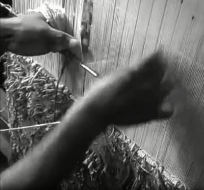 A weaver works at the loom, building a handwoven rug knot by knot at the House of Bohi workshop in Bhadohi, India.